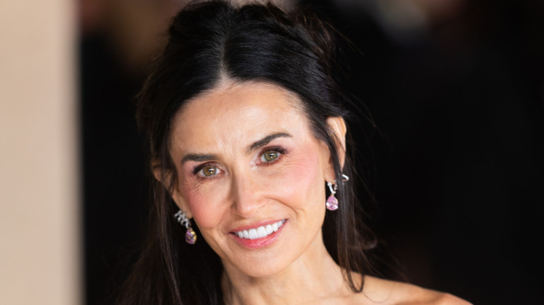 Demi Moore poses at a premiere in a floral gown and wears her hair half up.
